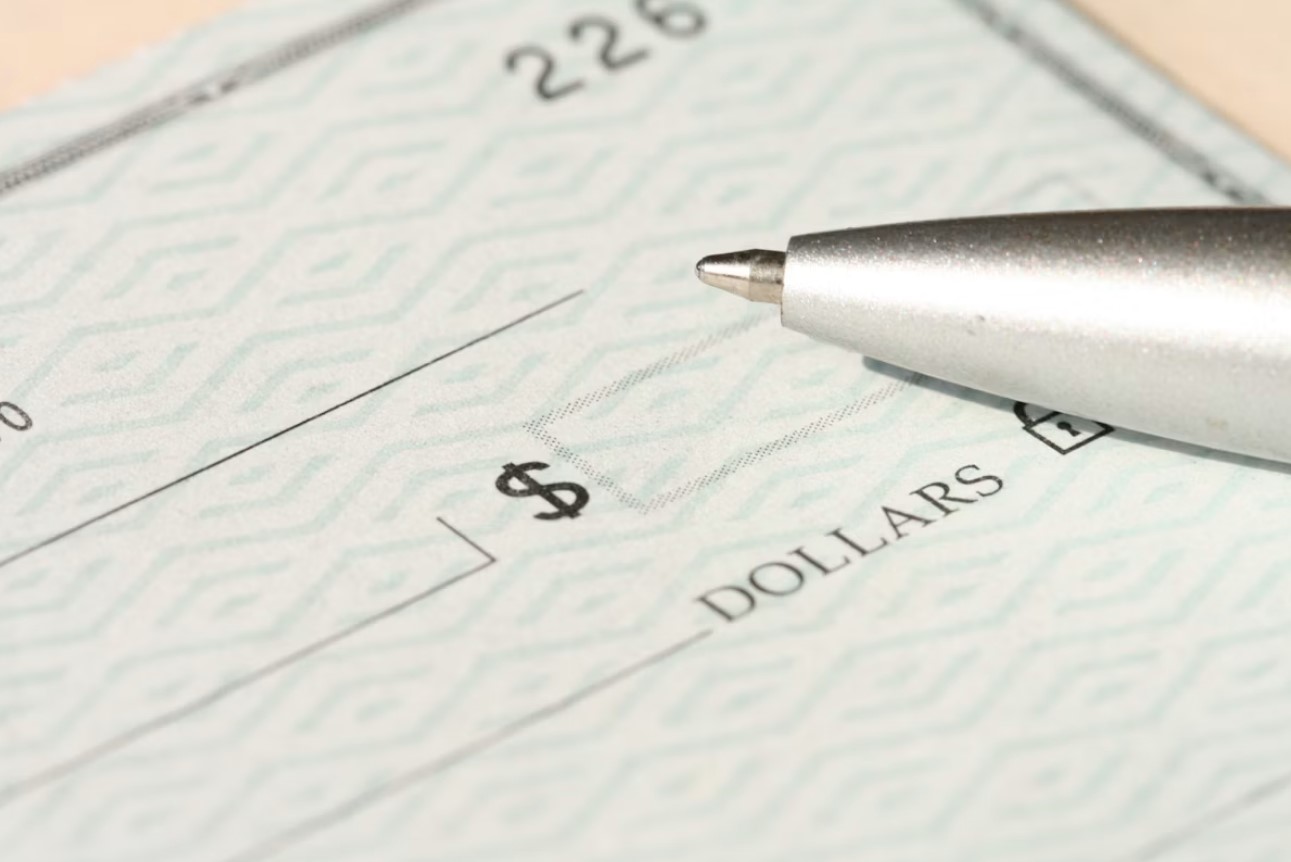 Pen resting on a check next to the dollars line